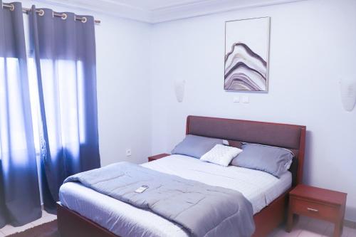 1 dormitorio con 1 cama grande con almohadas azules en MARIBART RESIDENCE - Électricité inclus, Forage, en Yaoundé