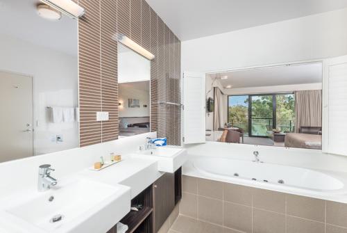 uma casa de banho com 2 lavatórios e um espelho grande em Macquarie 4 Star em Warners Bay