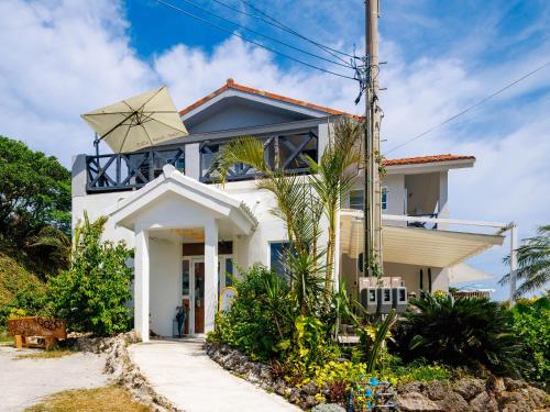 a white house with a sign in front of it at CoCo Resort Sesoko in Motobu