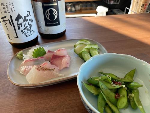 a plate of meat and a bowl of vegetables and a bottle of wine at ゲストハウス and BAR CHITEN in Awaji