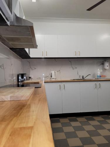 a kitchen with white cabinets and a checkered floor at Travellers Paradise Heritage Historical Guest House in Cairns