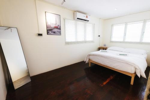 una camera da letto con un letto con lenzuola bianche e due finestre di monstera guesthouse (Lenggong) a Kampong Ulu Jepai