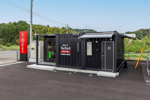 a bus stop with a black building next to a gas station at HOTEL R9 The Yard Satsumasendai in Satsumasendai