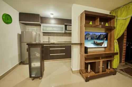 une cuisine avec une télévision sur une étagère et une cuisine avec un comptoir dans l'établissement Apartamento con Oficina, Cerca al Metro, à Sabaneta