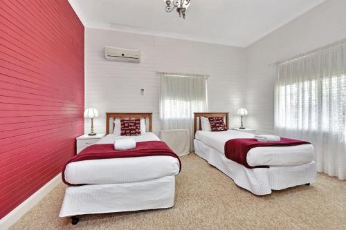 two beds in a bedroom with red and white walls at Tabitha Hill Cottage close to wineries and nature in Bellbird