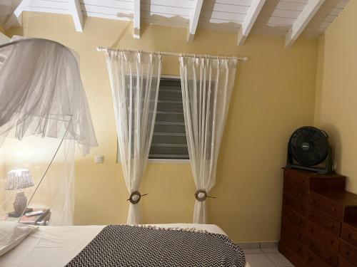 a bedroom with a bed and a window with curtains at Villa CECILIA in Oyster Pond