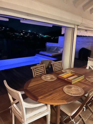 a wooden table and chairs on a balcony at night at Villa CECILIA in Oyster Pond