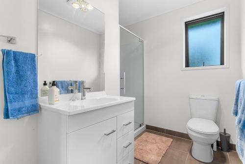 a white bathroom with a sink and a toilet at Mangawhai Maketu - Mangawhai Holiday Home in Mangawhai