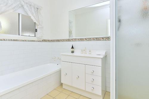 a white bathroom with a tub and a sink and a mirror at Tabitha Hill Homestead close to wineries and nature in Bellbird