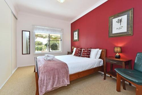 a bedroom with red walls and a bed and a chair at Tabitha Hill Homestead close to wineries and nature in Bellbird