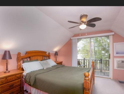 a bedroom with a bed with a ceiling fan and a window at Lovely waterfront private cottage with hot tub in Kawartha Lakes in Head Lake
