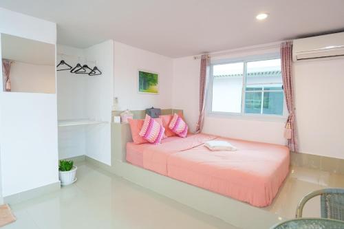a bedroom with a bed with pink pillows and a window at เขาค้อออฟเลิฟ in Khao Kho