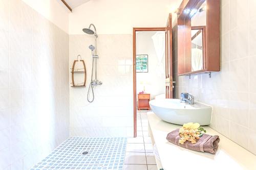 a white bathroom with a sink and a shower at Bungalow de 2 chambres a Bouillante a 70 m de la plage avec vue sur la mer piscine partagee et jardin clos in Bouillante
