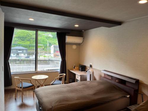 1 dormitorio con cama, escritorio y ventana en Ryokan Tenryu en Hita