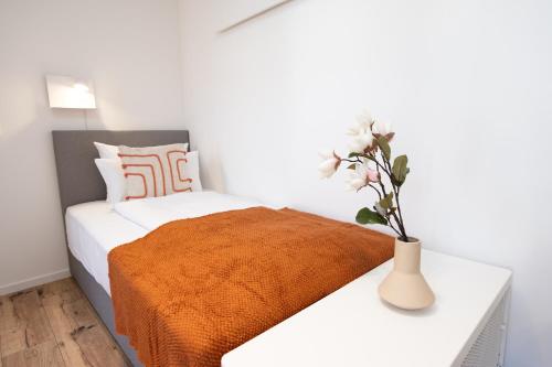 a bedroom with a bed with a vase of flowers on a table at DWELLSTAY - Zuse Höfe Bad Hersfeld in Bad Hersfeld