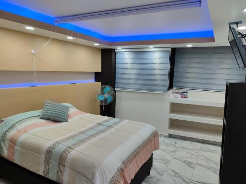 ein Schlafzimmer mit einem Bett und einer blauen Decke in der Unterkunft Departamento ejecutivo de lujo in Atlacomulco de Fabela