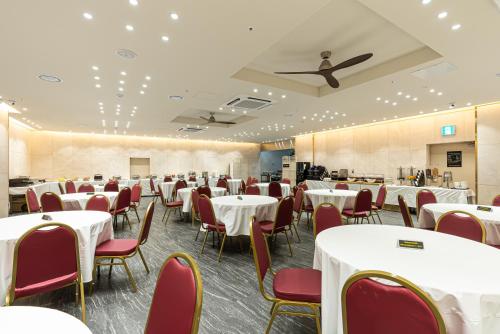 a banquet hall with white tables and red chairs at Hotel The Grang Seogwipo in Seogwipo