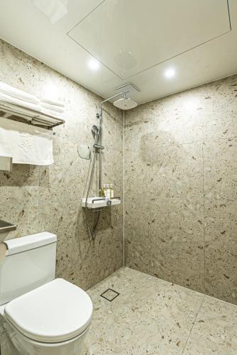 a bathroom with a toilet and a shower at Hotel The Grang Seogwipo in Seogwipo