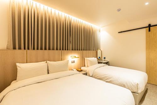 a bedroom with two beds and a window at Hotel The Grang Seogwipo in Seogwipo