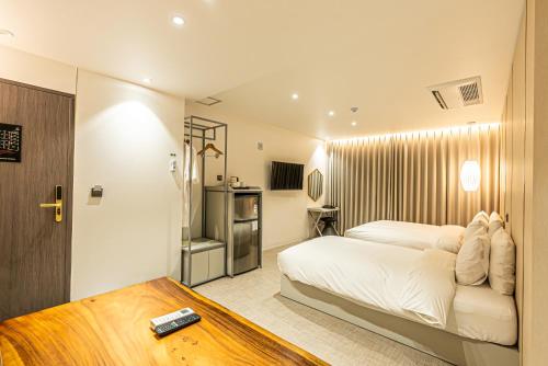 a bedroom with a white bed and a table at Hotel The Grang Seogwipo in Seogwipo