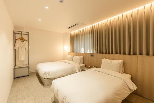 a hotel room with two beds and a window at Hotel The Grang Seogwipo in Seogwipo