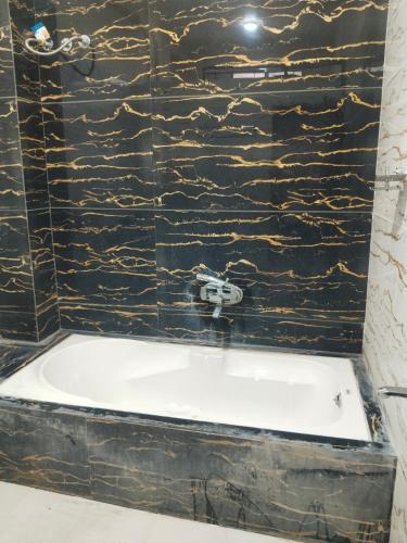 a bath tub in a bathroom with a black stone wall at Saanidhya home stay in Ujjain