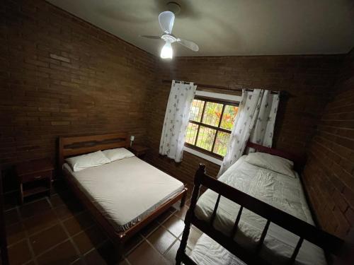 1 Schlafzimmer mit 2 Betten und einem Fenster in der Unterkunft Casa Rústica Alemã - 50m da praia in Ubatuba