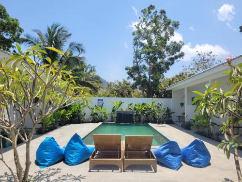a swimming pool with two chairs and blue pillows at Kahurangi Hotel in Sekongkang