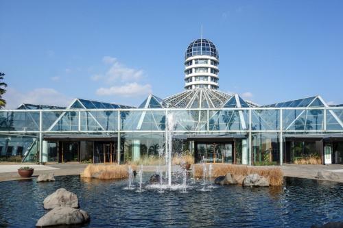 ein Glasgebäude mit einem Brunnen davor in der Unterkunft Hotel The Grang Jungmun in Seogwipo