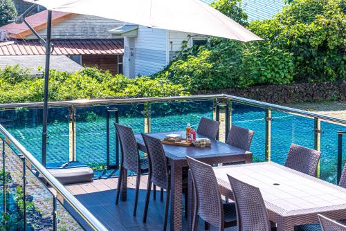 a patio with a table and chairs and an umbrella at Hotel The Grang Jungmun in Seogwipo