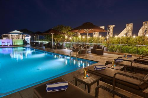 Belmont Hotel Manila في مانيلا: مسبح الفندق بالطاولات والكراسي في الليل