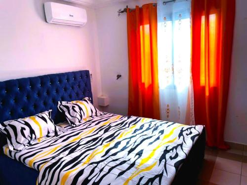una camera da letto con letto e lenzuola e tende zebrate di Makeena Berry Cosy Mboa -- a Douala