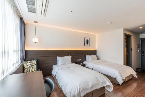 two beds in a room with a table and chairs at Hotel The Grang Jungmun in Seogwipo