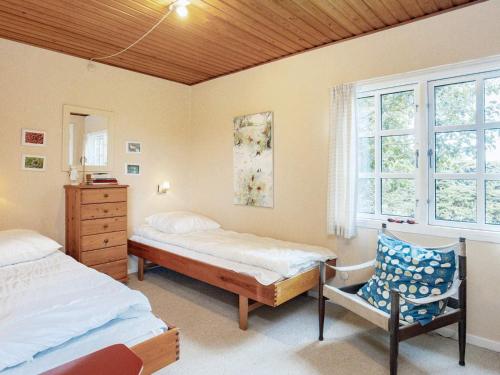 a bedroom with two beds and a chair and windows at Holiday home Frørup VI in Frørup