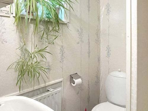 a bathroom with a toilet and plants on the wall at Holiday home GÖTENE II in Götene