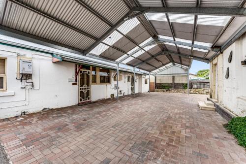 an open garage with a roof over a brick driveway at Wyatt Guest House in Mount Gambier