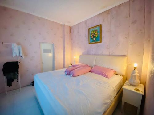 a bedroom with a bed with pink pillows on it at Villa Benny Gsp Cipanas in Cibadak