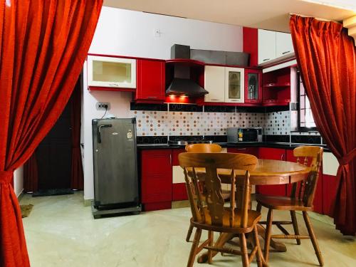 uma cozinha com armários vermelhos, uma mesa e cadeiras em OCEAN PEARL RESIDENCY em Cochin