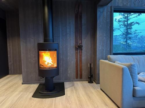 a fireplace in a living room with a couch at Stylish cabin at Lifjell with jacuzzi and sauna in Bø