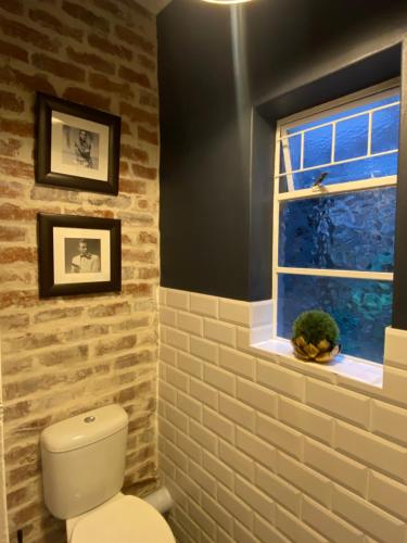 a bathroom with a white toilet and a window at Eclectic Heritage Paradise Simon's Town in Simonʼs Town