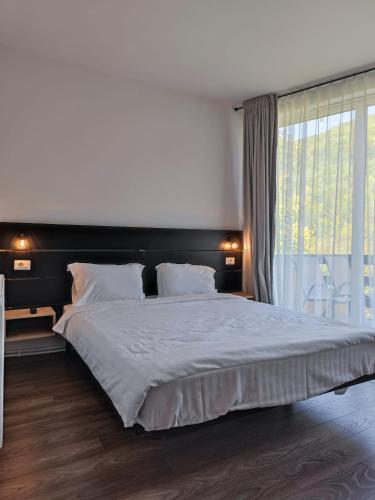 a bedroom with a large bed with a large window at Izvorul lui Dracula in Râşnov