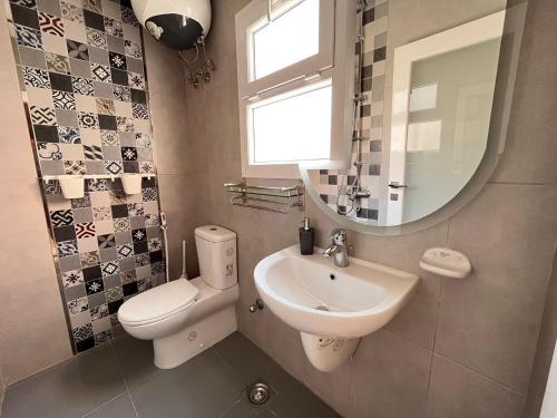 ein Badezimmer mit einem Waschbecken, einem WC und einem Spiegel in der Unterkunft Boka Bay One in Hurghada