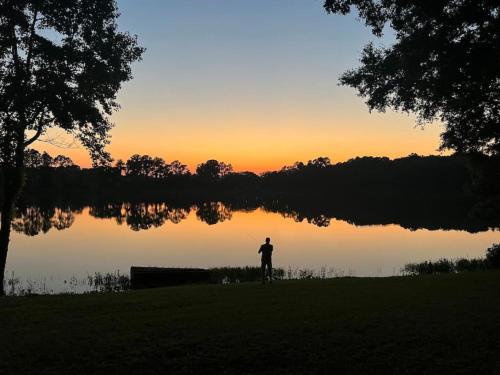 a person standing in front of a lake at sunset at Hammock Trail Lake - Lake Park - Valdosta Area in Lake Park