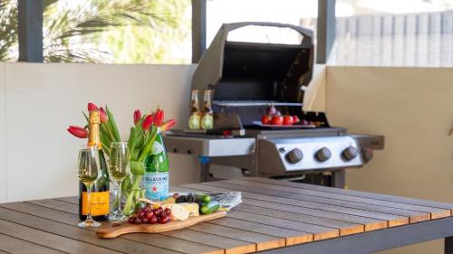 a table with wine bottles and a tray of food and flowers at Bliss - seaside retreat in Callala Beach