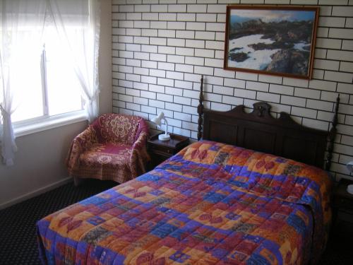 a bedroom with a bed and a chair at Colonial Lodge Motel in Belmont