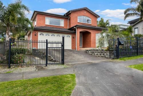 a brick house with a gate and a driveway at Albany Bolthole with Queen Beds and Kitchenette in Auckland