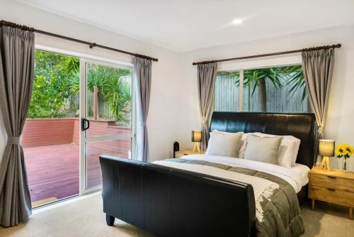 um quarto com uma cama e uma porta de vidro deslizante em Albany Bolthole with King Beds and Kitchenette em Auckland