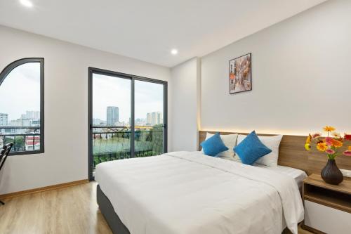 a white bedroom with a large bed with blue pillows at 22housing Residence Suites in Hanoi
