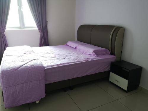 sypialnia z łóżkiem z fioletową pościelą i oknem w obiekcie Metropol Suite w mieście Bukit Mertajam