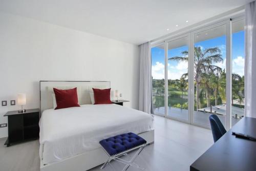 a bedroom with a white bed and a large window at Las Palmas 16 Chef, Butler, Maid and Golf Cart in Punta Cana